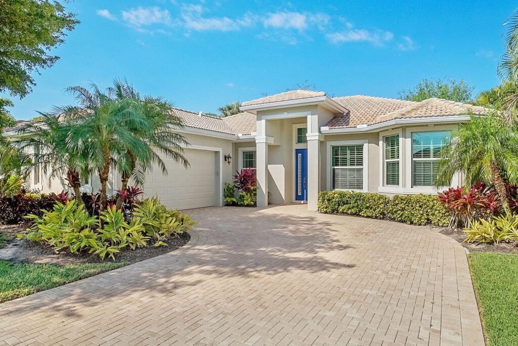 a realistic photo of a well-maintained Southwest Florida rental home with tropical landscaping, a clean driveway, and a residential setting.